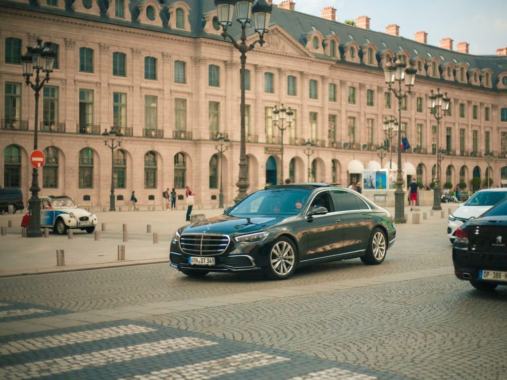 A Mercedes Benz driving in front of the historic Ritz building in Paris.
