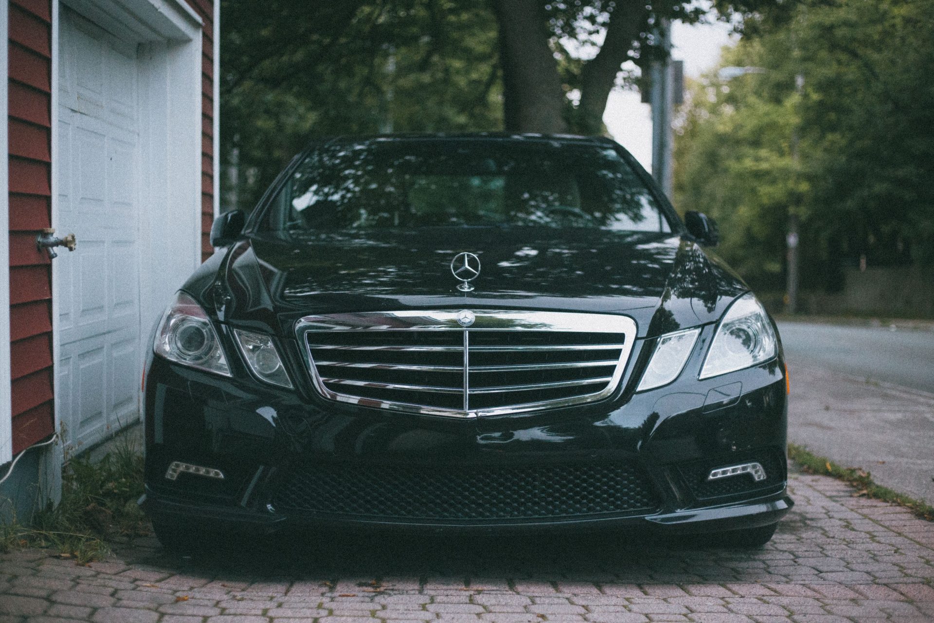 Front view of a parked Mercedes-Benz showcasing its sleek design on a brick driveway.