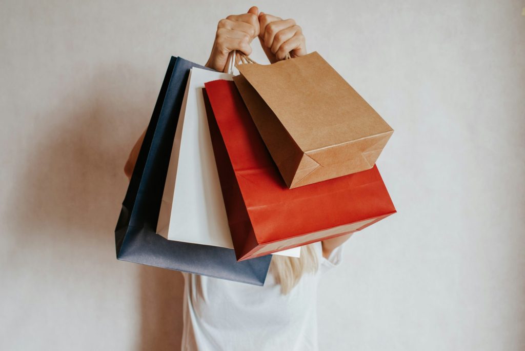 Person holding colorful shopping bags in front of face