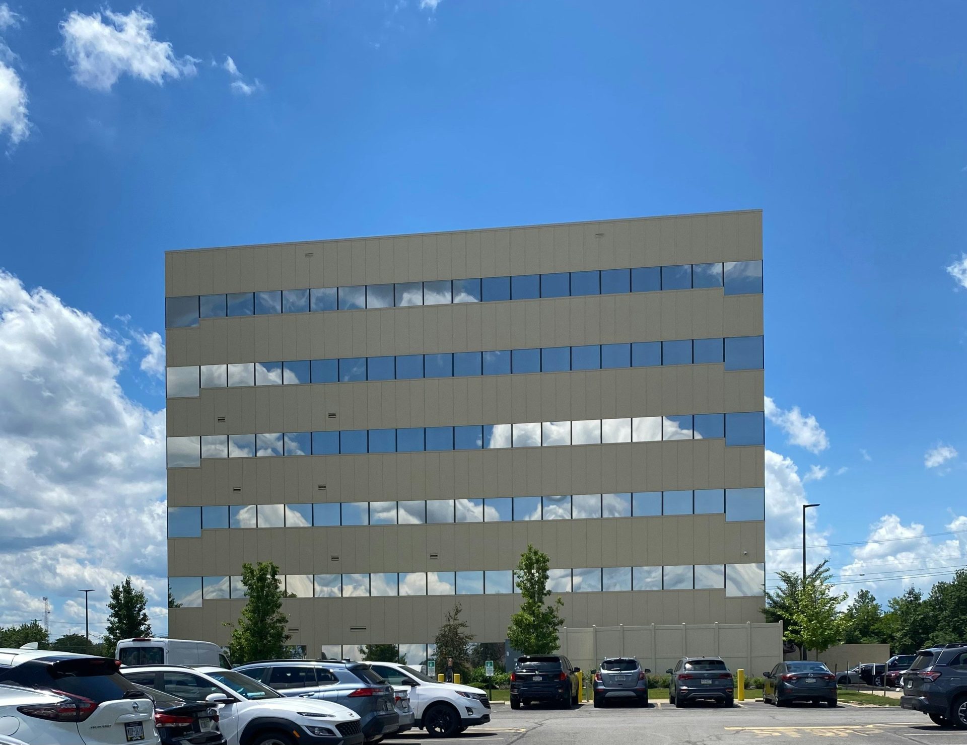 Modern office building with cloud reflections and a parking lot