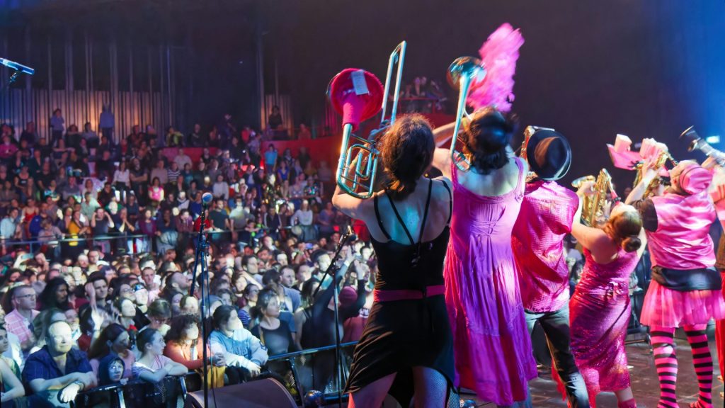Performers in pink costumes on stage with audience